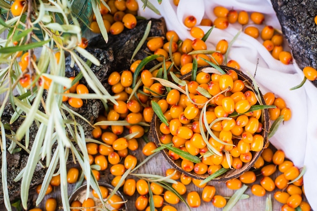 Berries of sea-buckthorn in a bowl on a wooden table. Top view