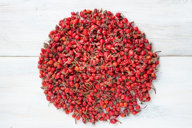 Berries of wild rose on white wooden background, fruit of red dog rose .