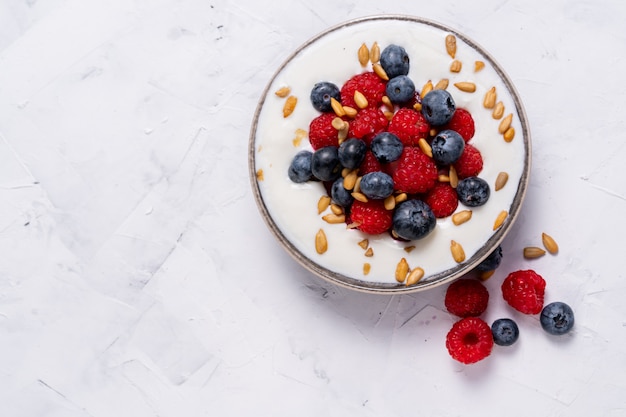 berries yoghurt in ceramic bowl on white table