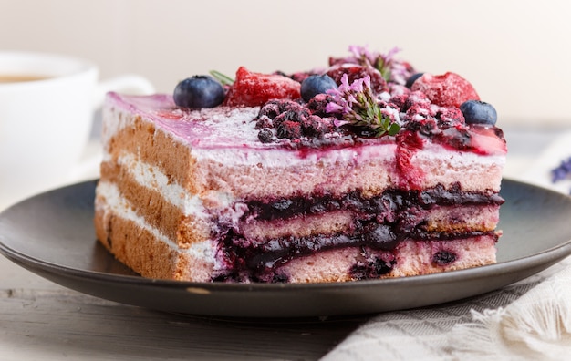 Berry cake with milk cream and blueberry jam on blue ceramic plate 