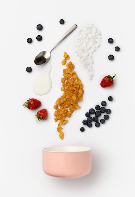 Фото Ягоды, кукурузные хлопья и йогурт наливают в керамическую миску для приготовления домашнего завтрака