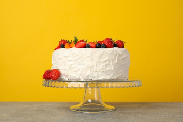 Berry cream cake against yellow background