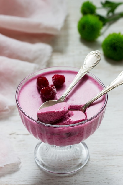 Berry-fruit mousse decorated with raspberries on a light\
background.