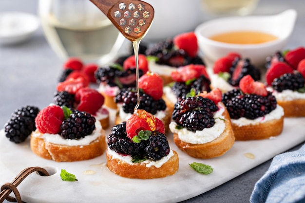 Photo berry and goat cheese bruschetta with mint and honey