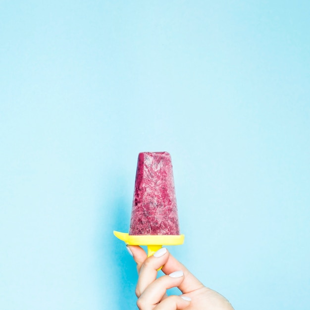 Berry homemade ice cream in a female hand on a blue background