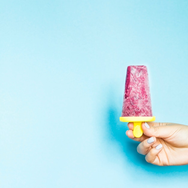 Berry gelato fatto in casa in una mano femminile su uno sfondo blu
