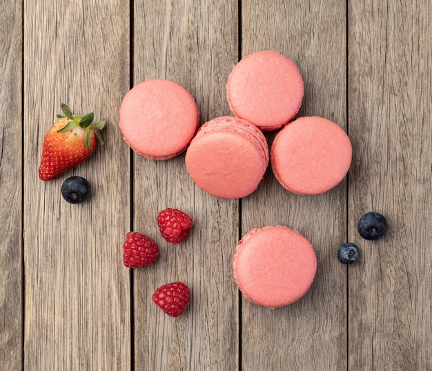 Berry macarons with strawberries raspberries and blueberries over wooden table