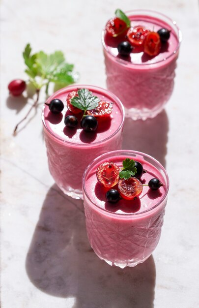 Berry mousse garnished with currants and gooseberries on a marble background. Selective focus.