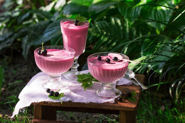 Berry mousse in glass vases on a wooden in the garden.