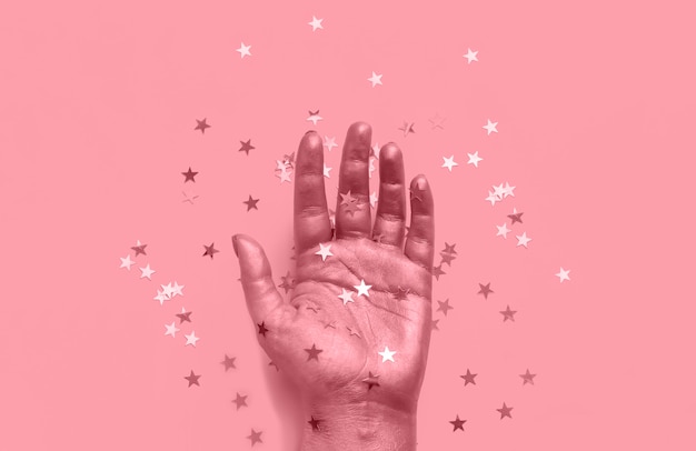 Photo berry pink toned hand with star confetti