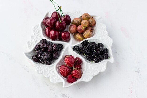 Ягодная тарелка на белом фоне Клубника крыжовник вишня малина и шелковица