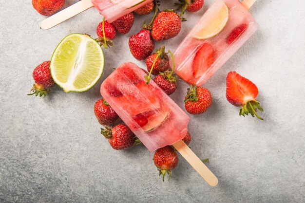 Berry Popsicle with wooden sticks on concrete counter. Homemade Strawberry Frozen Fruit Bars