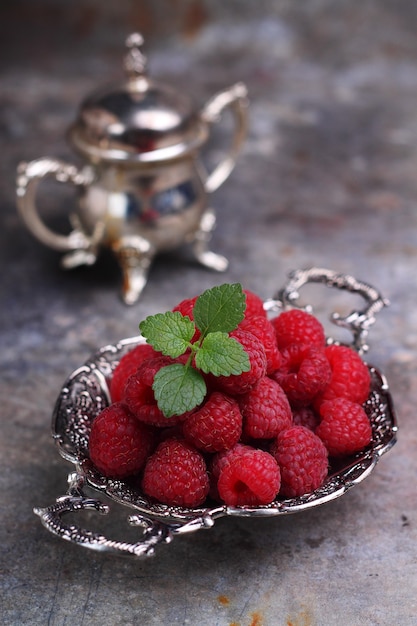 Berry red raspberry and mint leaf in a vintage bowl