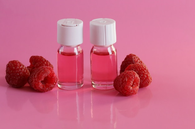 berry serum and raspberries on a pink table