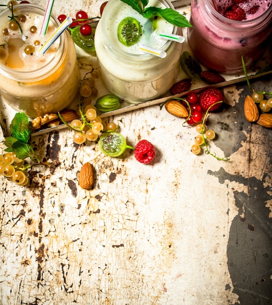 Berry smoothie made from currants, gooseberries and raspberries with nuts on rustic table.