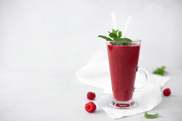 Berry smoothie met verse frambozen en munt in een hoog glasglas, close-up