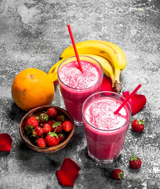 Photo berry smoothie with banana and rose petals on rustic background