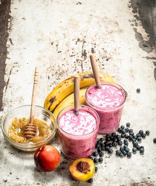 Foto frullato di frutti di bosco con banana. su fondo rustico.