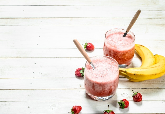 Berry smoothie with banana on a white wooden background