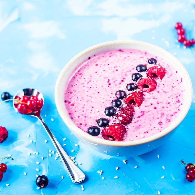 Berry smoothies met krenten en frambozen op een heldere blauwe achtergrond