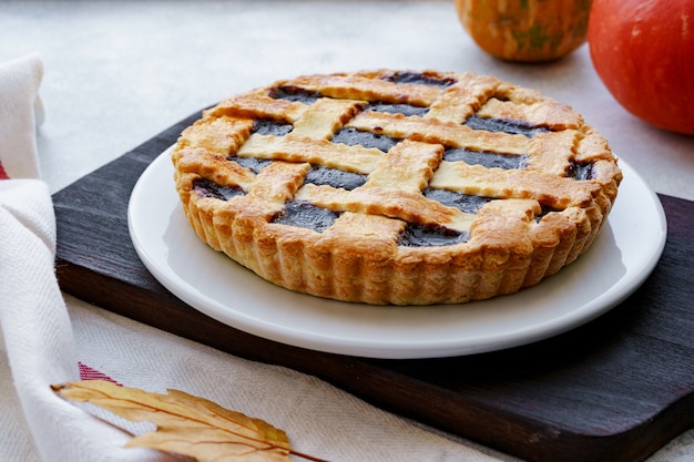 Berry tart pie and orange pumpkin on wooden table close up