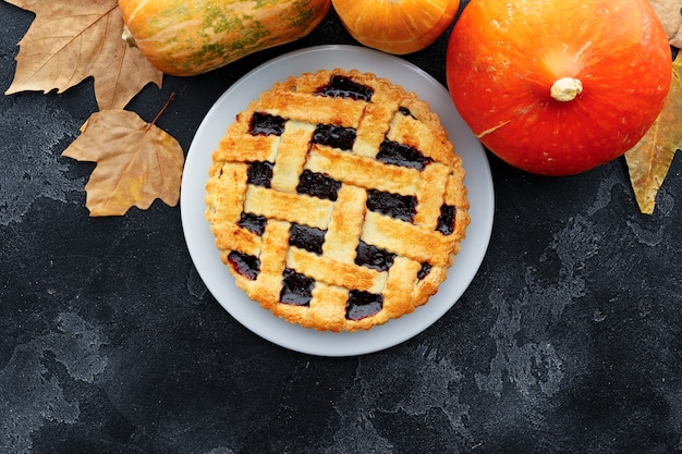 Berry tart pie and orange pumpkin on wooden table