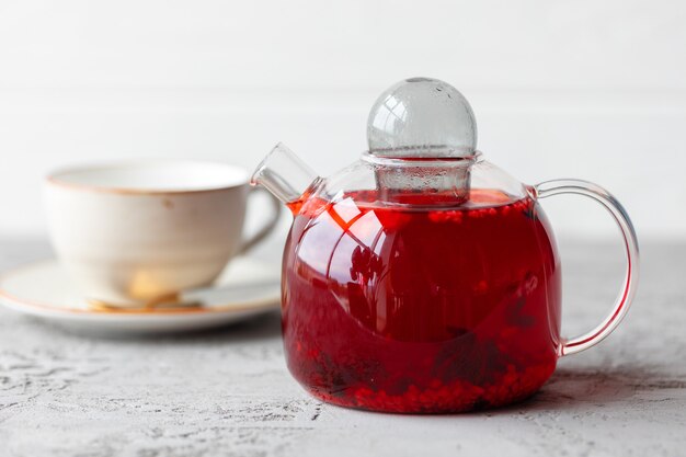 Berry tea in glass teapot on gray surface