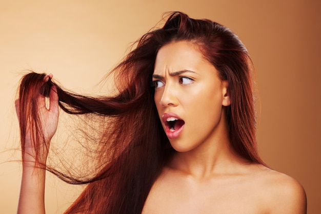 Beschadigd haar en een vrouw die van streek is in de studio over een salon met een gespleten uiteinde en een kappersbehandeling Stressramp en geschokte modelpersoon met een droge textuur of kapselcrisis op een bruine achtergrond