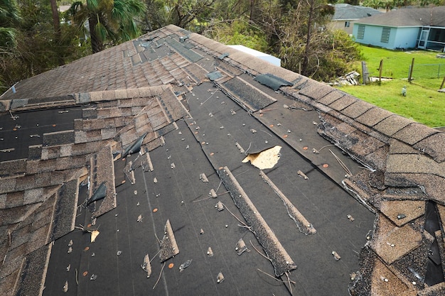 Beschadigd huisdak met ontbrekende dakspanen na orkaan Ian in Florida Gevolgen van natuurramp