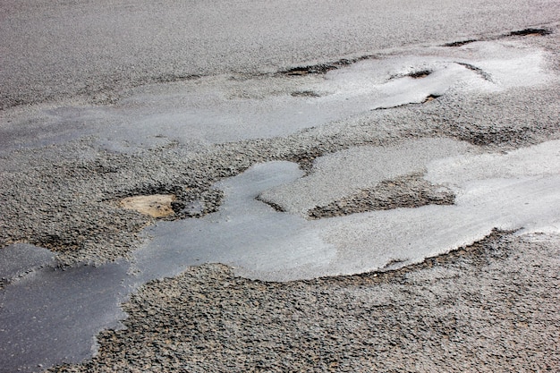 Beschadigde asfaltweg met gatenReparatie van gaten in de wegen Reparatie van asfaltwegen