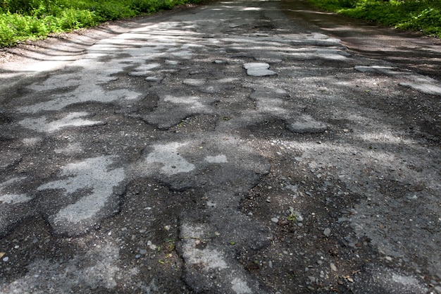 Beschadigde weg vol gebarsten kuilen in bestrating