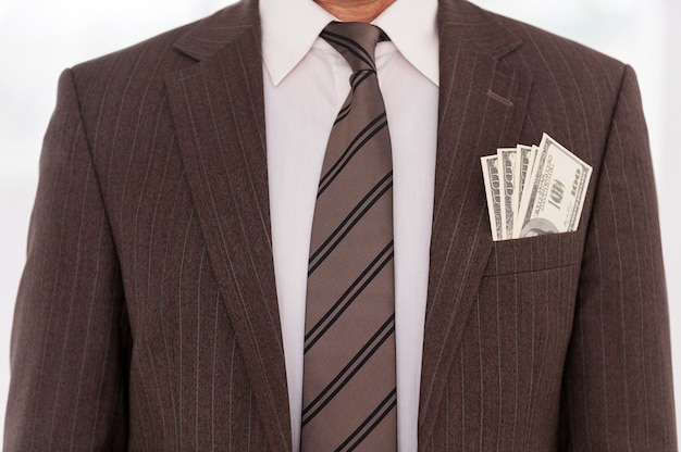 Foto beschadigde zakenman. close-up van zakenman in formalwear met geld dat zich uit zijn zak uitstrekt