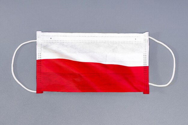 Beschermend gaasmasker met vlag van Polen op grijze achtergrond Medisch beschermend masker op grijze achtergrond