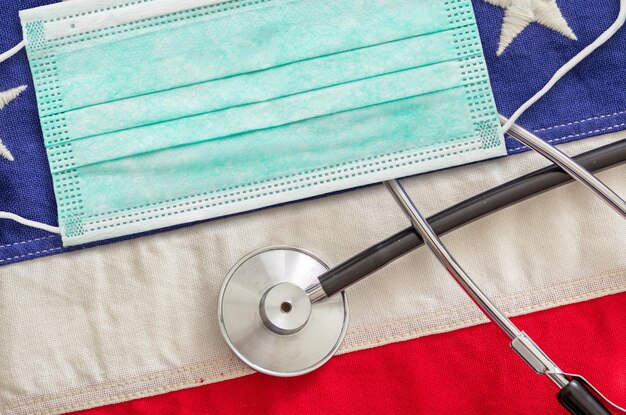 Beschermend gezichtsmasker en medische stethoscoop op de Amerikaanse vlag achtergrond Coronavirus concept