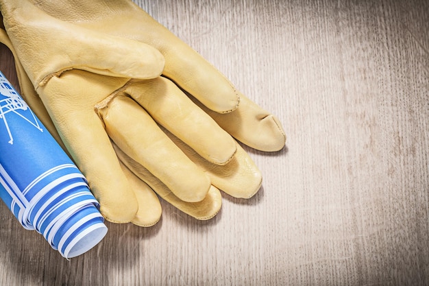 Beschermende handschoenen blauwe blauwdrukken op houten plank bouwconcept.