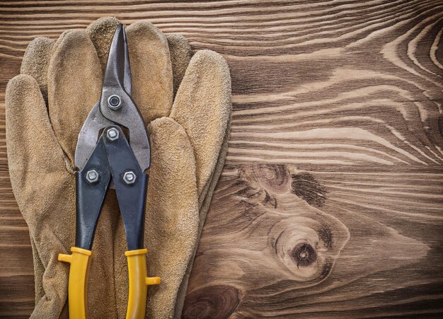 Beschermende handschoenen metalen blik knipt op houten plank bouwconcept.