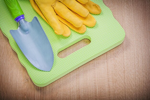 Beschermende handschoenen tuinschuim knielende pad hand schop op houten plank tuinieren concept.