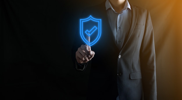 Bescherming netwerkbeveiligingscomputer in de handen van een zakenman. zaken, technologie, cyberveiligheid en internet concept - zakenman op schildknop op virtuele schermen te drukken. Gegevensbescherming.