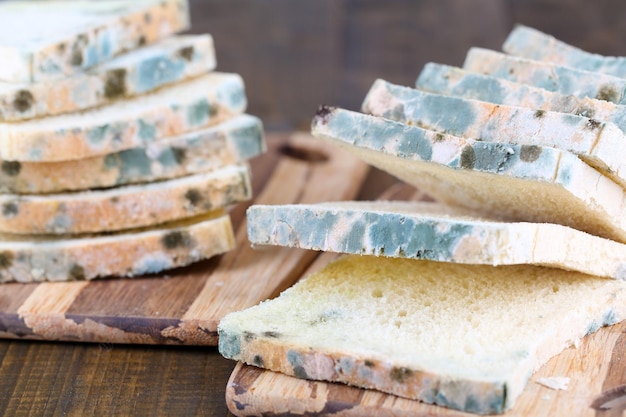 Beschimmeld brood op snijplank op houten achtergrond