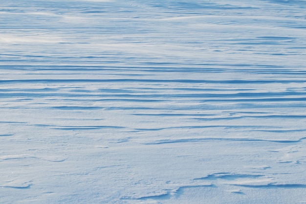 Besneeuwde achtergrond, besneeuwde oppervlakte van de aarde na een sneeuwstorm in de ochtend in het zonlicht met verschillende lagen sneeuw