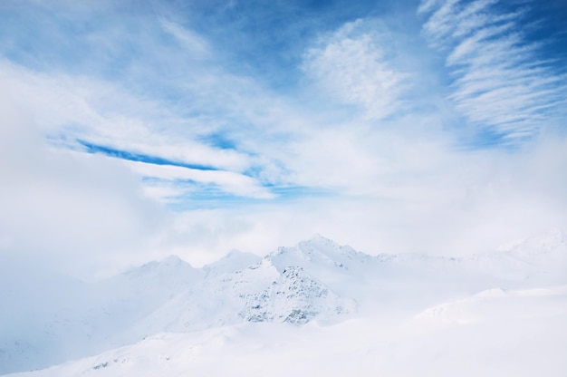 Besneeuwde bergen en blauwe lucht met witte wolken. Prachtig winterlandschap.