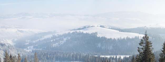 Besneeuwde bergen in de winter met witte wolken in de blauwe lucht