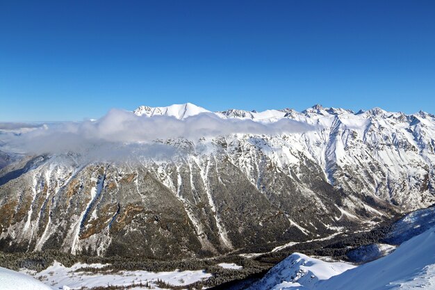 Besneeuwde bergen toppen in de wolken blauwe lucht Kaukasus