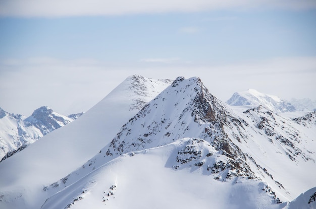 Besneeuwde bergen toppen in de wolken blauwe lucht Kaukasus