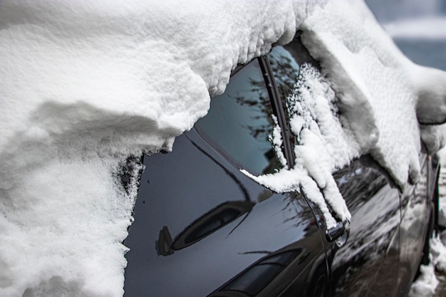 Besneeuwde bevroren auto bedekt met sneeuw Winterweg Gevaar voor rijden in de winter Auto sneeuwruimen Gevaarlijke verkeerssituatie