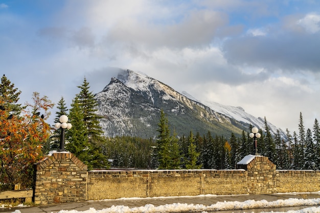 Besneeuwde Mount Rundle-bergketen met besneeuwd bos over blauwe lucht en witte wolken in de winter