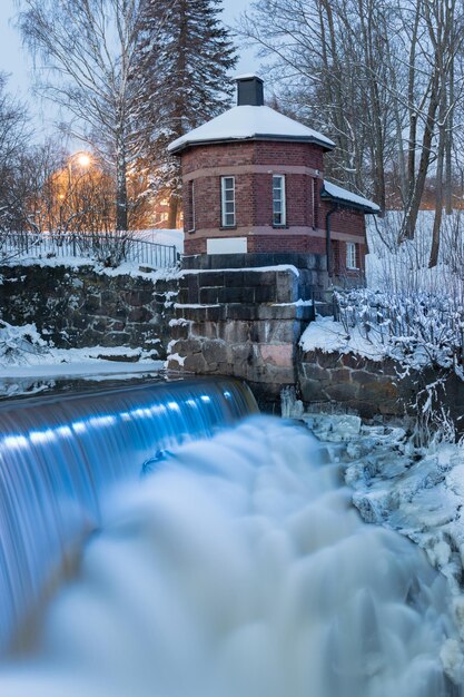 besneeuwde scène van een kleine waterval met een blauw licht op het water Helsinki Finland