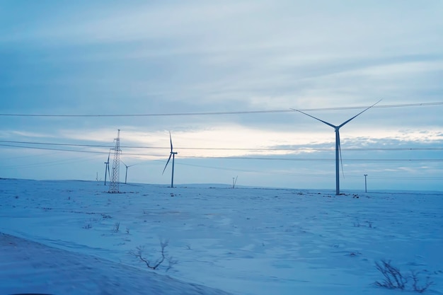 Besneeuwde veld en windturbine bij zonsopgang in de winter. Luchtfoto van de natuur in de winter. Alternatieve energiebronnen. Milieuvriendelijke elektriciteit