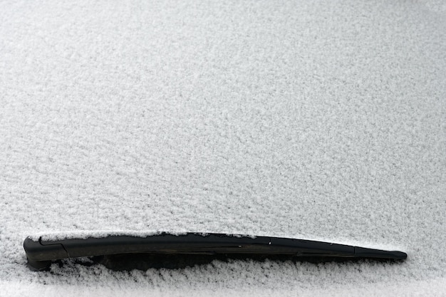 Besneeuwde voorruit op een auto met ruitenwissers Winterconcept voor verkeer en verkeersveiligheid