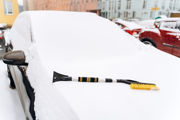 Besneeuwde winter. close-up van de auto met de speciale borstel op de motorkap. apparaat voor het reinigen van sneeuw uit het autoconcept. stock foto